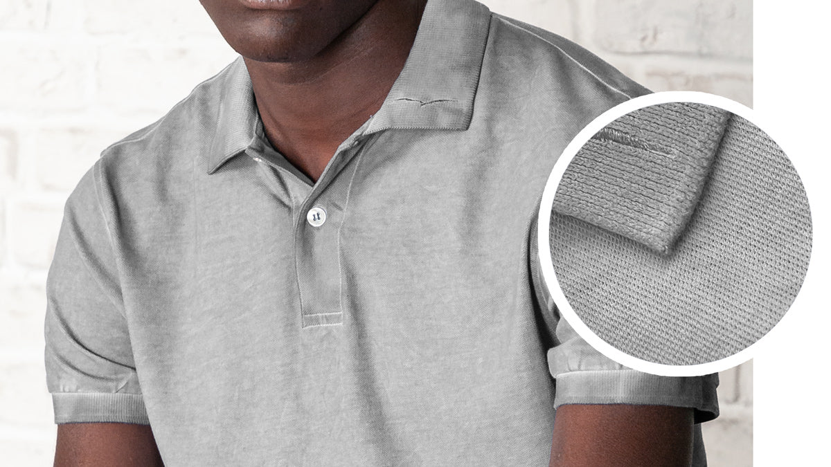 Close up shot of a gray pique polo shirt with magnification of the collar and body texture.